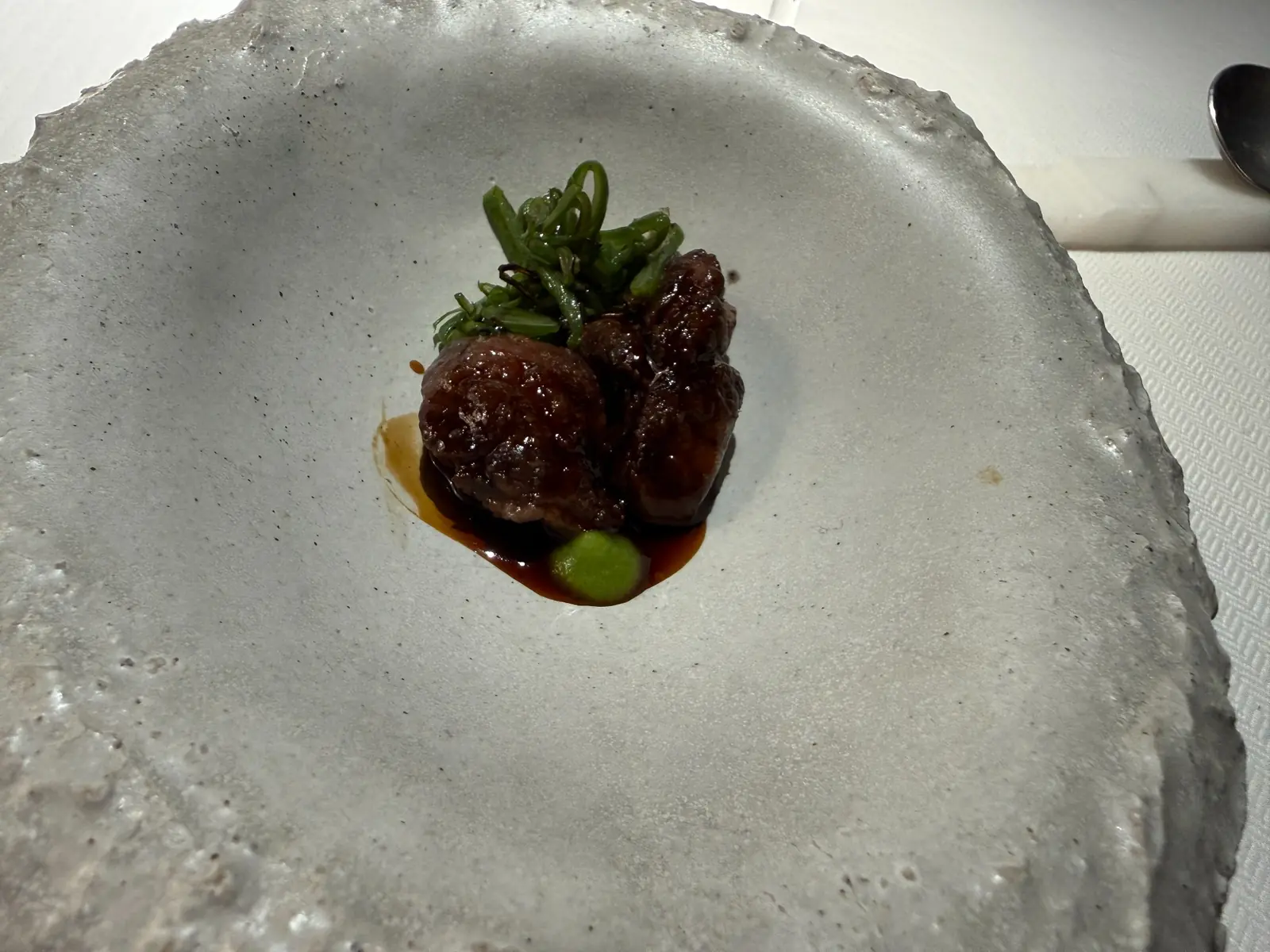 Plato del menú Pardo con salsa y pequeños detalles verdes
