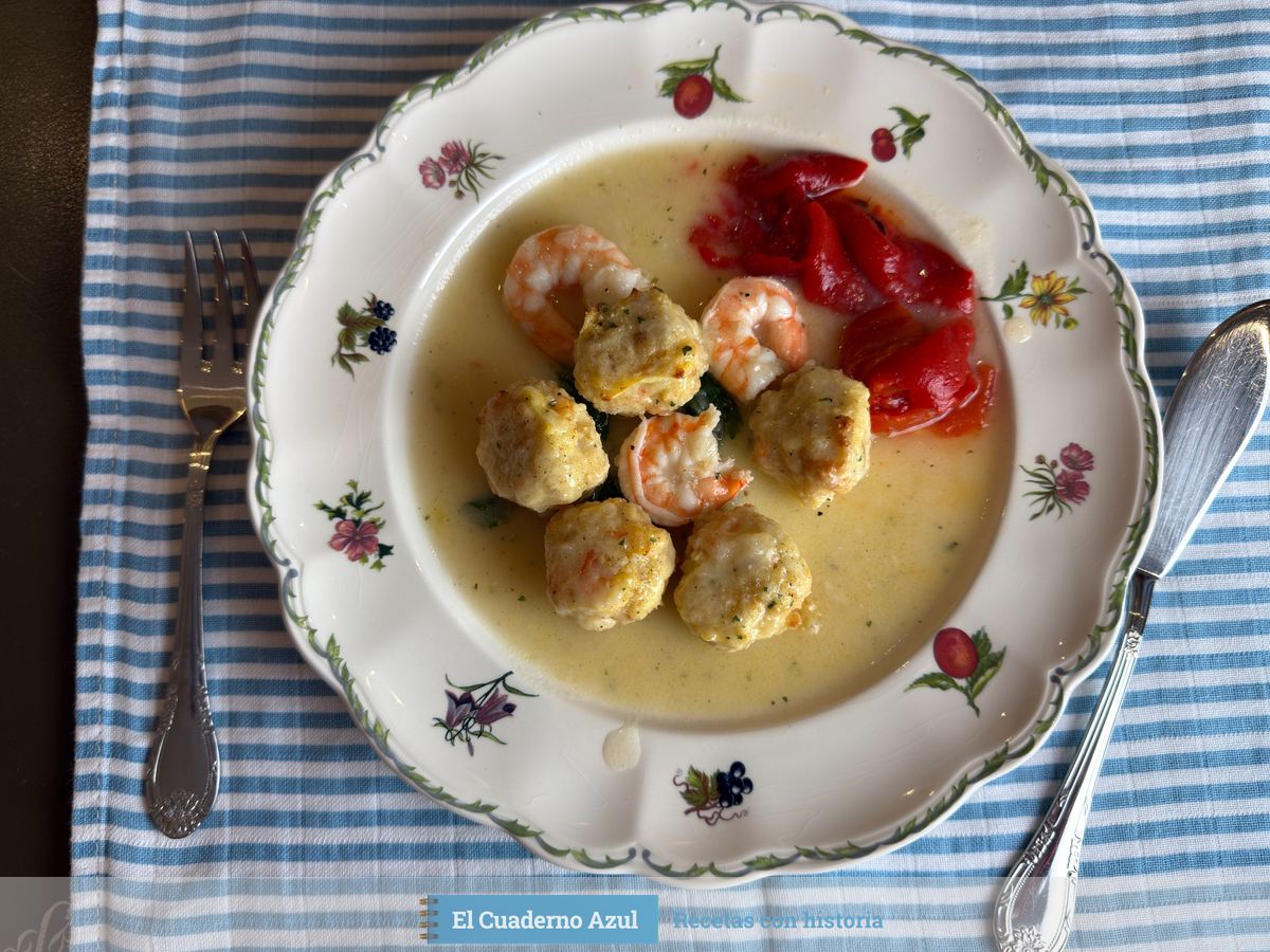 Albóndigas de merluza en salsa verde con gambas enteras y tiras de pimiento rojo en un plato de flores