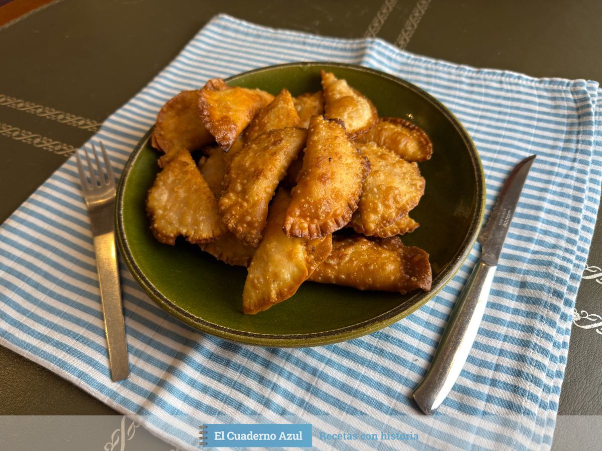 Empanadillas fritas de bonito con tomate en un plato verde sobre un paño de rayas